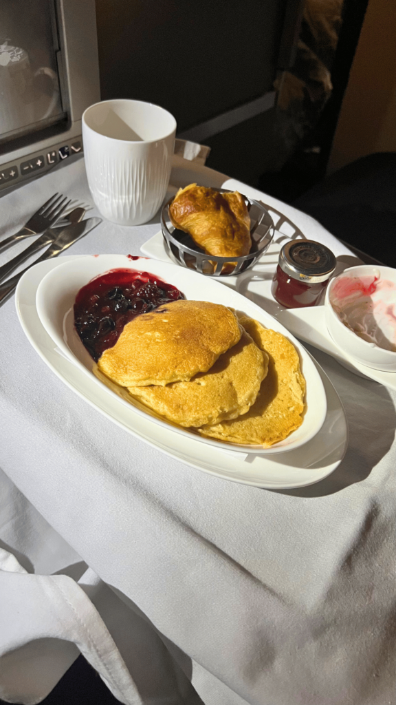 Breakfast Pancakes on British Airways A380 | Journey Beyond 40 a plate of fluffy breakfast pancakes served on british airways a380, topped with syrup and fresh fruit.