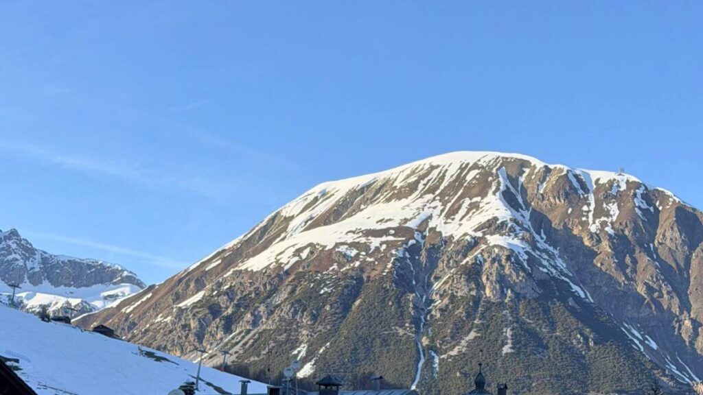 a scenic view of snow-capped mountain peaks in the european alps during the sunny march ski season.