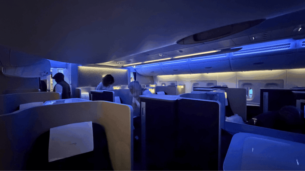British Airways First Class Cabin with Blue LED Lighting | Journey Beyond 40 wide angle view of the modern british airways first class cabin featuring private suites and ambient blue led mood lighting.